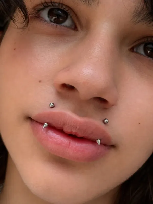 Close de piercing snake bites com joias prateadas no lábio inferior, resultado da Memphis em Taboão da Serra