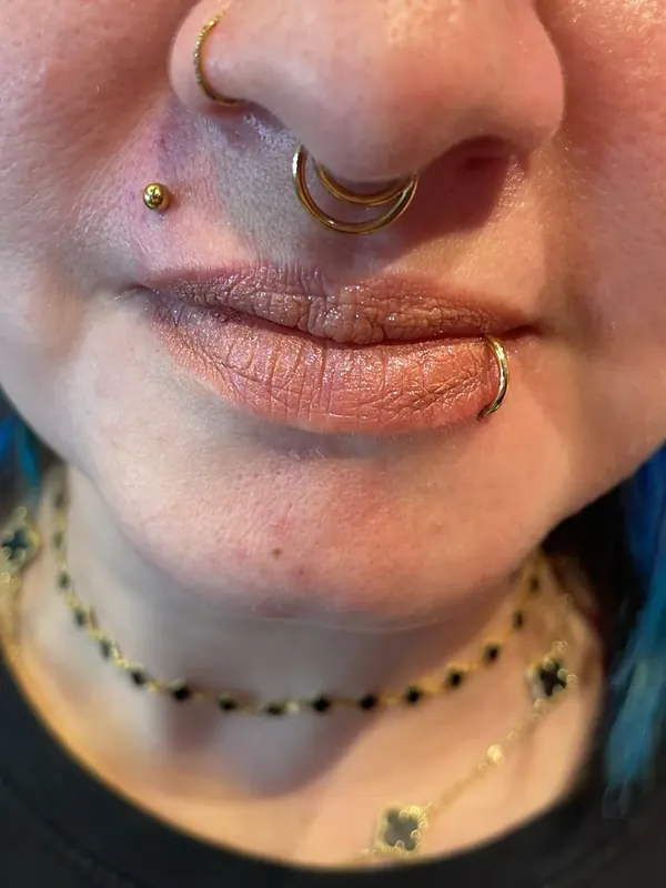 Piercing no nariz com argola dourada e septo, aplicados pela Memphis no Shopping Taboão