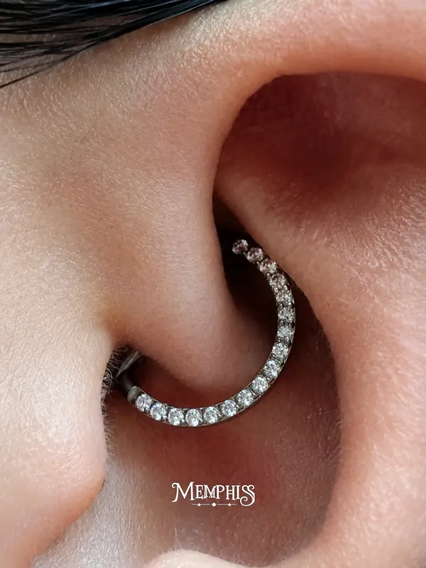 Daith com argola cravejada de zircônias contornando a curva da orelha