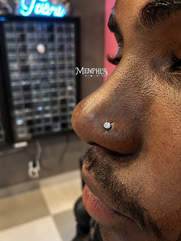 Piercing nostril com ponto de luz em pele negra, na loja do Shopping Taboão