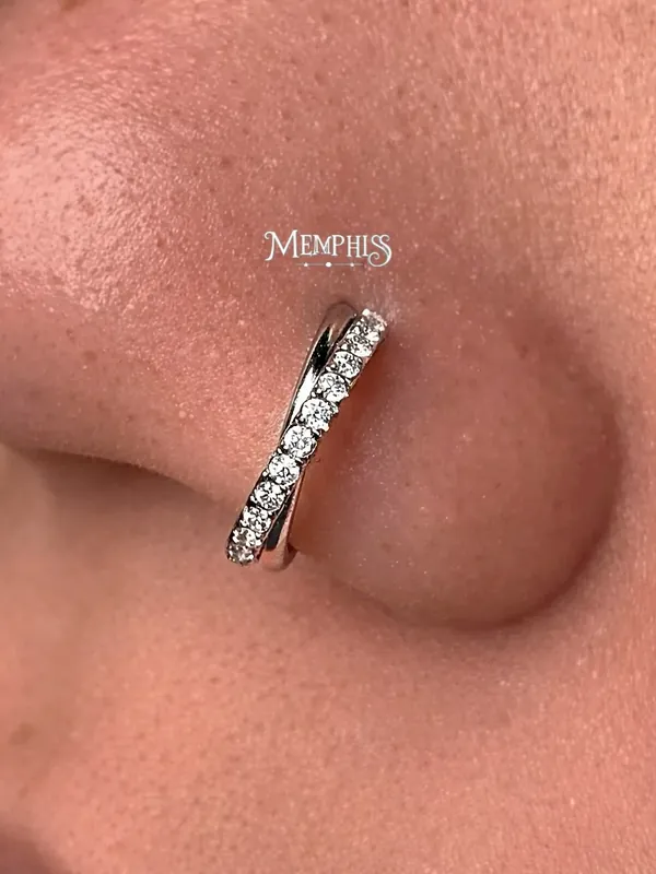 Piercing nostril com joia curva cravejada acompanhando a narina