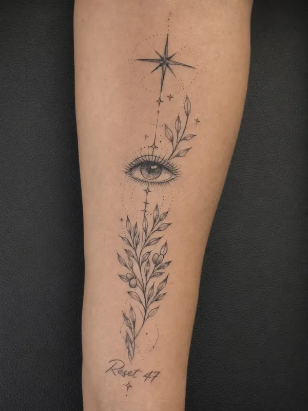 Tatuagem fine line de olho, estrela e ramo de oliveira no antebraço, com a frase Reset 47 abaixo